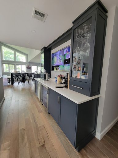 Modern kitchen space with dark cabinetry, a counter, and a wall-mounted TV.