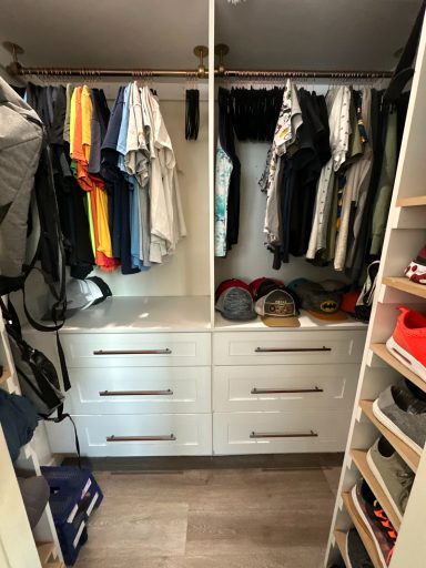 A neatly organized closet with clothes hanging and drawers below.