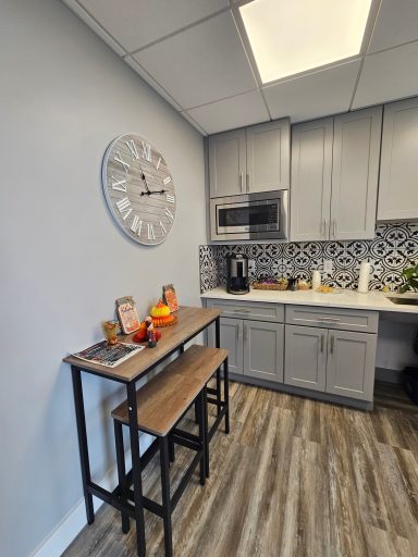 Modern kitchen with a clock, microwave, and a dining table with decor.