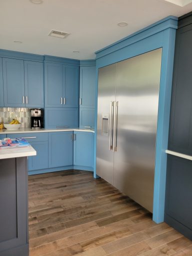 Modern kitchen featuring blue cabinets and a stainless steel refrigerator.