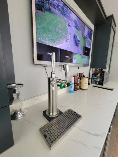 A sleek countertop with a beer tap and a monitor displaying outdoor security footage.