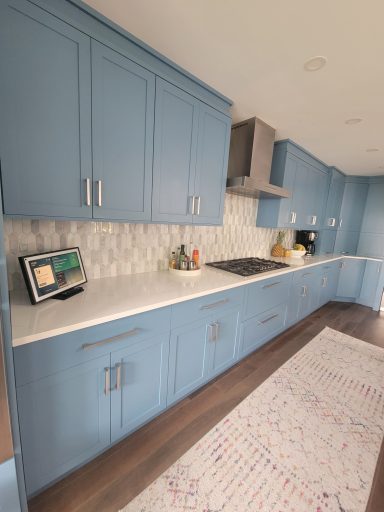 Modern kitchen with blue cabinets, white countertops, and a patterned rug.