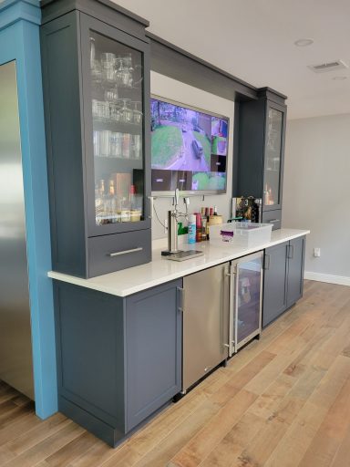 Modern kitchen bar with dark cabinets, a countertop, and a beverage fridge.