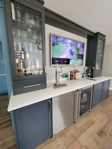Modern kitchen bar with a TV, glass cabinets, and a sleek countertop.